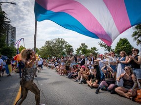 A person waves a trans pride flag during the Pride Parade at English Bay in Vancouver on Sunday, Aug. 6, 2023.