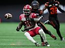Calgary Stampeders' Marken Michel, front, makes the reception as he's hit by B.C. Lions' Emmanuel Rugamba during the first half of a CFL football game, in Vancouver, on Saturday, August 12, 2023.