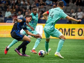 San Jose Earthquakes' Cade Cowell (44) battles Vancouver Whitecaps' Ranko Veselinovic (4) and Whitecaps' Richie Laryea (7) during first half MLS soccer action in Vancouver on Sunday, August 20, 2023.