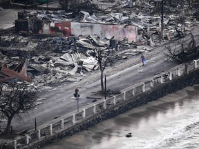 An aerial image taken on Aug. 10, 2023 shows a person walking down Front Street past destroyed buildings burned to the ground in Lahaina in the aftermath of wildfires in western Maui, Hawaii.