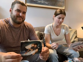 Robie and Sophie Holland go through photographs of themselves with their father, who died in recent inland flooding in Nova Scotia, in Tantallon, N.S., Friday, Aug. 11, 2023.