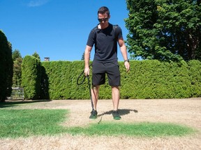 Tyler Basham, owner of Tinted Turf Grass Solutions, applies non-toxic grass paint with a sprayer to a parched and yellow lawn at a residence in Surrey. Due to tighter water restrictions, residents of Metro Vancouver are no longer allowed to water their lawns.