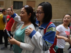 A student waves to her friends as she prepares to leave with her mother after she finished a college entrance exam at a school in Beijing.
