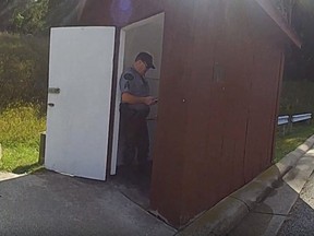 In this photo released by the Michigan State Police, a Department of Natural Resources sergeant stands in the doorway of an outhouse after a woman became trapped in the toilet after attempting to retrieve her Apple Watch, Tuesday, Sept. 19, 2023, at Dixon Lake in Bagley Township, Mich.