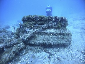 This Aug. 17, 2021 photo shows quagga mussels cover the engine of a Bell P-39 Airacobra military plane in Lake Huron, Mich., as maritime archeologist Carrie Sowden, rear, documents the site.