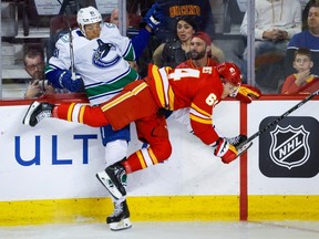 Vancouver Canucks' Dakota Joshua, left, is checked by Calgary Flames' Ben Jones during first period NHL preseason hockey action in Calgary, Sunday, Sept. 24, 2023.