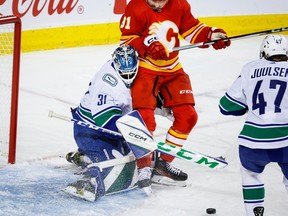 Vancouver Canucks goalie Artors Silovs, left, keeps track of the puck as Calgary Flames forward Nazem Kadri crashes into him during first period NHL preseason hockey action in Calgary, Sunday, Sept. 24, 2023.