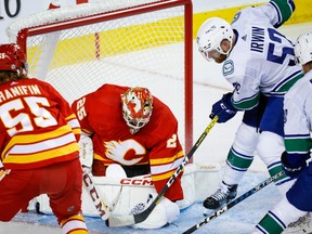 Vancouver Canucks' Matt Irwin and Aatu Raty dig for the puck as Calgary Flames goalie Jacob Markstrom covers it up during second period NHL preseason hockey action in Calgary, Sunday, Sept. 24, 2023.