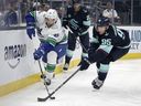 Vancouver Canucks defenseman Guillaume Brisebois and Seattle Kraken left wing Andre Burakovsky battle for the puck during the first period of an NHL hockey preseason game, Thursday, Sept. 28, 2023, in Seattle.