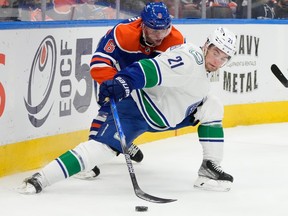Edmonton Oilers Ben Gleason (6) and Vancouver Canucks Nils Hoglander (21) battle for the puck behind the net during second period NHL preseason action on Wednesday, Sept. 27, 2023 in Edmonton.