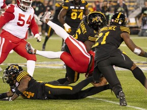 Calgary Stampeders running back Ka'Deem Carey (35) is tackled by Hamilton Tiger Cats defensive end Malik Carney (5) and Hamilton Tiger Cats linebacker Simoni Lawrence (21) during first half CFL football game action in Hamilton, Ont., Saturday, Sept. 30, 2023.