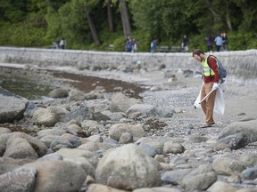 File photo of a volunteer cleaning up plastic garbage from the shoreline at Second Beach in Vancouver.