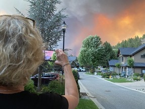 Wendy Creelman takes photos of the West Kelowna wildfire from in front of her house in Kelowna's Glenmore Highlands, not long before she and her daughter, Alexa, visiting from Vancouver, were forced to flee after the fire jumped Okanagan Lake.