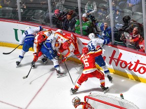 Abbotsford Canucks and Calgary Wranglers players battle along the boards at the Abbotsford Centre on Friday, October 20, 2023.