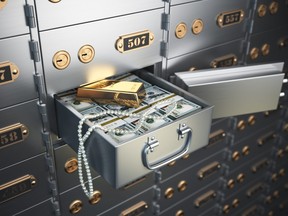 Open safe deposit box with money, jewels and golden ingot.