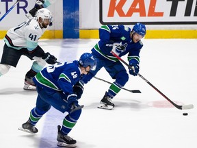Vancouver Canucks' Pius Suter (24) skates with Cole McWard (48) while being chased by Seattle Kraken's Pierre-Edouard Bellemare (41) during the second period of preseason NHL action in Abbotsford, B.C. on Wednesday, Oct. 4, 2023.
