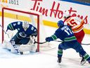 Vancouver Canucks goaltender Thatcher Demko stops Calgary Flames' Dryden Hunt (15) as Canucks' Filip Hronek  defends during the first period of an NHL preseason hockey game in Vancouver  Oct. 6, 2023.