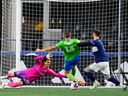 Vancouver Whitecaps goalkeeper Yohei Takaoka reaches out as Seattle Sounders forward Jordan Morris prepares to strike the ball, and Whitecaps defender Tristan Blackmon, right, defends against Morris during the first half of an MLS soccer match Saturday, Oct. 7, 2023, in Seattle.