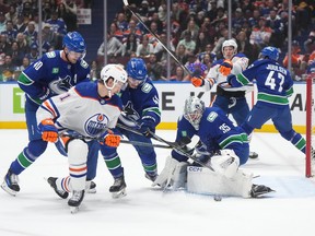 Vancouver Canucks goalie Thatcher Demko (35) stops Edmonton Oilers' Ryan McLeod, front left, as Vancouver's Akito Hirose (41) and Elias Pettersson (40) defend during the first period at Rogers Arena on Wednesday