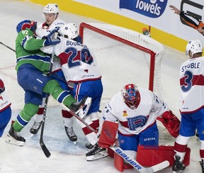 Abbotsford Canucks' Vasily Podkolzin (92) crashes the net and gets a glove in the face from Laval Rocket's Gabriel Bourque (20) beside goaltender Jakub Dobes (71) during the second period on Friday.