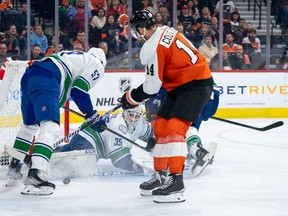 Vancouver Canucks' Thatcher Demko (35) looks for the puck along with Tyler Myers (57) and Philadelphia Flyers' Sean Couturier (14) after making the save during the second period on Tuesday in Philadelphia.