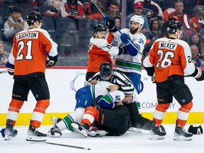 Vancouver Canucks' Noah Juulsen (47) gets into it with Philadelphia Flyers' Marc Staal, bottom, as the official tries to pull Juulsen off during the third period on Tuesday, Oct. 17, 2023, in Philadelphia. The Flyers won 2-0.