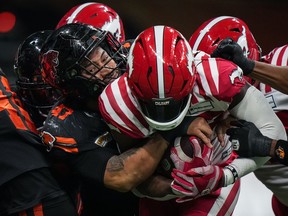 B.C. Lions' Sione Teuhema, left, tackles Calgary Stampeders' Ka'Deem Carey during the first half of a CFL football game, in Vancouver, on Friday, October 20, 2023.