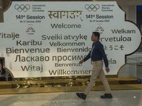 A man walks past a welcome sign at the entrance on the first day of the 141st International Olympic Committee (IOC) session in Mumbai, India, Sunday, Oct. 15, 2023.