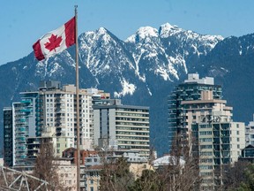Strong winds keep a Canadian Flag fluttering as the Westend of downtown Vancouver, BC is framed by snow-capped mountains Tuesday, March 28, 2023. (Photo by Jason Payne/ PNG) (For story by reporter) [PNG Merlin Archive] TAG: Dentsu photo option