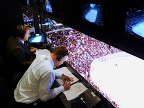 Sportsnet's John Shorthouse (R) jots down a note during a break in play at a regular season NHL game between the Vancouver Canucks and the Nashville Predators at Rogers Arena on Oct. 20 2011.