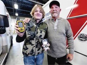 Thirteen-year-old Carter Burkard shows the GPS device he used to help rescue his grandfather, John Burkard, right, after an ATV accident. The teen was presented with a Good Samaritan Award by B.C. Emergency Health Services in Victoria, Oct. 26, 2023. DARREN STONE, TIMES COLONIST