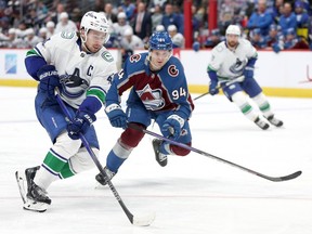 Quinn Hughes of the Vancouver Canucks advances the puck against Joel Kiviranta of the Colorado Avalanche in the third period at Ball Arena on November 22, 2023 in Denver, Colorado.