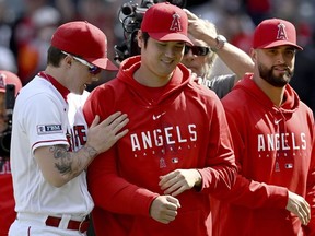 Los Angeles Angels' Mickey Moniak, left, walks with Shohei Ohtani, center, after playing against the Oakland Athletics in a baseball game Sunday, Oct. 1, 2023, in Anaheim, Calif.