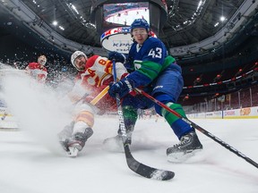 Calgary Flames defenceman Christopher Tanev and Vancouver Canucks defenceman Quinn Hughes vie for the puck during a game at Rogers Arena in Vancouver in May 2021.