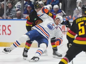 Edmonton Oilers' Leon Draisaitl, front, is hauled down by Vancouver Canucks' Dakota Joshua during the first period on Monday at Rogers Arena.