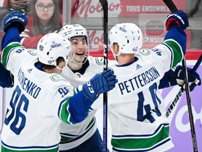Vancouver Canucks' Ilya Mikheyev (65) celebrates with teammates Andrei Kuzmenko (96) and Elias Pettersson (40) after scoring against the Montreal Canadiens during second period NHL hockey action in Montreal, Sunday, November 12, 2023.