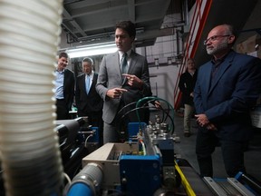 Prime Minister Justin Trudeau listens to Chief Technical Officer Brian Way (right) as Premier David Eby (rear left) talks with Nelson Chang, chairman of TCC Group, E-One Moli Energy (Canada), while touring the lithium battery manufacturer E-One Moli Energy in Maple Ridge on Tuesday.