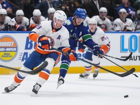New York Islanders' Brock Nelson, front left, and Vancouver Canucks' Elias Pettersson vie for the puck during the first period on Wednesday night at Rogers Arena.