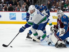 Vancouver Canucks centre J.T. Miller, front left, reaches out for the puck next to Colorado Avalanche defenceman Cale Makar (8), while goaltender Alexandar Georgiev watches during the second period on Wednesday night