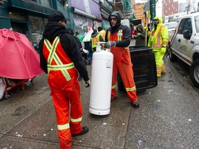 City works crews remove an industrial-size propane tank from a tent on East Hastings Street in Vancouver in April.