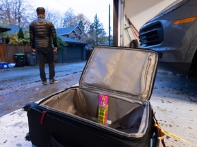 Marcus Xu with suitcase in his garage from which his father's ashes were stolen.