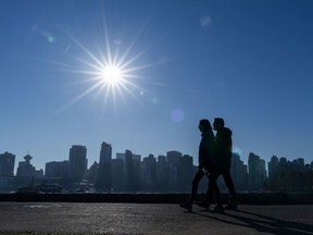 A couple walks along the seawall in Stanley Park while enjoying a dry day in Vancouver.