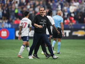 Vancouver Whitecaps head coach Vanni Sartini is restrained by a member of the team's staff after he went on the field and tried to get to referee Tim Ford after he received a red card during the second half in game 2 of a first round MLS playoff soccer match against Los Angeles FC, in Vancouver, on Sunday, November 5, 2023.