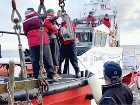 In an image taken from a video shared online by Ryan Planes, the rescued boater, in the green toque at left, waves to the crew that spotted his life raft 74 kilometres off Tofino. VIA RYAN PLANES