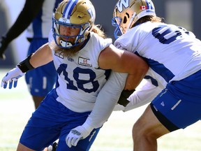 Utility man Damian Jackson (left) wraps around offensive guard Geoff Gray during Winnipeg Blue Bombers practice on Tuesday, Sept. 26, 2023.