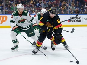 Jonas Brodin #25 and Brock Faber #7 of the Minnesota Wild defend against J.T. Miller #9 of the Vancouver Canucks during the first period of their NHL game at Rogers Arena on December 7, 2023 in Vancouver, British Columbia, Canada.