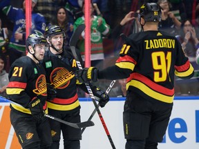 Nils Hoglander #21 is congratulated by J.T. Miller #9 and Nikita Zadorov #91 of the Vancouver Canucks after scoring a goal against the Minnesota Wild during the first period of their NHL game at Rogers Arena on December 7, 2023 in Vancouver, British Columbia, Canada.