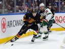 Andrei Kuzmenko of the Canucks is checked by Jonas Brodin of the Wild during the third period of their NHL game at Rogers Arena on Dec. 7, 2023.