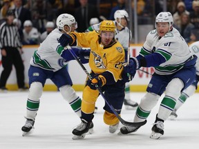 Ryan McDonagh of the Nashville Predators battles Nikita Zadorov of the Vancouver Canucks for control of the puck at Bridgestone Arena on December 19, 2023 in Nashville, Tennessee.