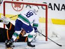 Vancouver Canucks forward Sam Lafferty, right, scores on Calgary Flames goalie Jacob Markstrom during first period of NHL game in Calgary, Saturday, Dec. 2, 2023.